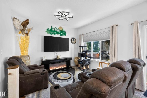 Living area with an electric fireplace, mounted television, and a ceiling-mounted light fixture - 91 Hilton Cove, Spruce Grove, AB - Indoor Photo Showing Living Room