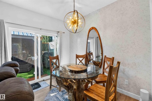 Sliding glass patio door, wood-finish flooring, textured wall finish, and a suspended light fixture - 91 Hilton Cove, Spruce Grove, AB - Indoor Photo Showing Dining Room
