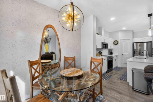 White cabinetry, stainless steel appliances, light wood-finish flooring, recessed lighting, and a modern kitchen island with an undermount sink - 91 Hilton Cove, Spruce Grove, AB - Indoor Photo Showing Dining Room