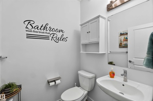 Pedestal sink with chrome faucet, wall-mounted storage cabinet, and large vanity mirror - 91 Hilton Cove, Spruce Grove, AB - Indoor Photo Showing Bathroom