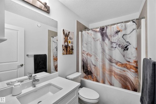 White vanity with integrated sink, chrome faucet, and a large wall-mounted mirror - 91 Hilton Cove, Spruce Grove, AB - Indoor Photo Showing Bathroom