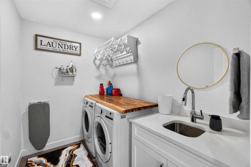 Laundry area featuring a wood-finish countertop, white cabinetry, undermount sink, and a chrome pull-down faucet - 91 Hilton Cove, Spruce Grove, AB - Indoor Photo Showing Laundry Room