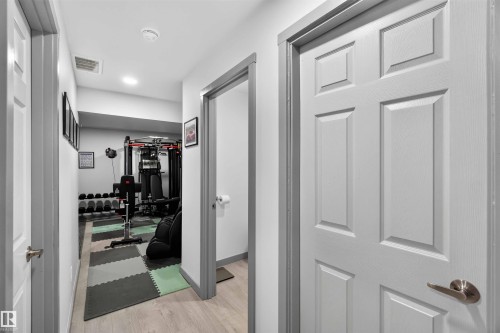 Hallway featuring light wood-finish flooring, white walls, and white paneled doors with brushed nickel hardware - 91 Hilton Cove, Spruce Grove, AB - Indoor Photo Showing Other Room