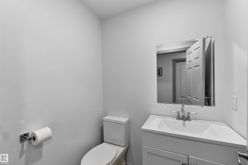 White single vanity with integrated sink, chrome faucet, wall-mounted mirror, and white toilet - 91 Hilton Cove, Spruce Grove, AB - Indoor Photo Showing Bathroom