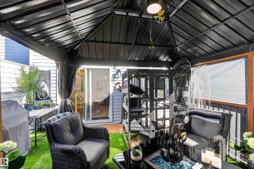 Covered patio with a black metal gazebo, integrated ceiling light fixture, and sliding glass door access - 91 Hilton Cove, Spruce Grove, AB - Outdoor With Deck Patio Veranda With Exterior