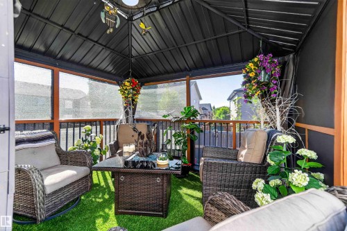 Covered outdoor structure with a dark metal roof, privacy screens, and a wood-finish railing - 91 Hilton Cove, Spruce Grove, AB - Outdoor With Deck Patio Veranda With Exterior