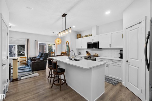 Open-concept living space with wood-finish flooring - 91 Hilton Cove, Spruce Grove, AB - Indoor Photo Showing Kitchen With Double Sink