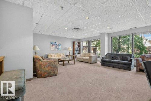 Spacious common area featuring neutral carpeting, a drop ceiling with recessed lighting, and large windows providing abundant natural light - #804 11027 87 Av Nw, Edmonton, AB - Indoor