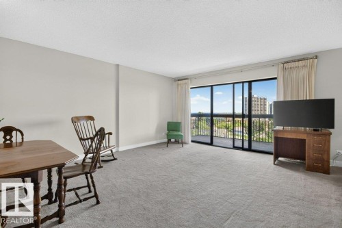 Bright living space featuring a full wall of glass doors opening to a balcony, light-toned carpeting, and neutral wall tones - #804 11027 87 Av Nw, Edmonton, AB - Indoor
