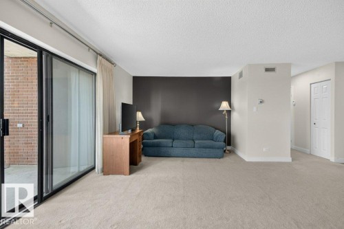 Spacious room featuring light-toned carpet flooring, a dark accent wall, and neutral painted walls - #804 11027 87 Av Nw, Edmonton, AB - Indoor