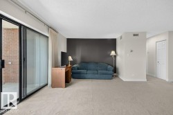 Spacious room featuring light-toned carpet flooring, a dark accent wall, and neutral painted walls - 