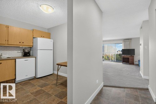 Kitchen area with wood-finish cabinetry, white subway tile backsplash, and white appliances - #804 11027 87 Av Nw, Edmonton, AB - Indoor Photo Showing Kitchen