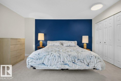 Bedroom featuring a bold accent wall, neutral carpeting, and a flush-mount ceiling light - #804 11027 87 Av Nw, Edmonton, AB - Indoor Photo Showing Bedroom