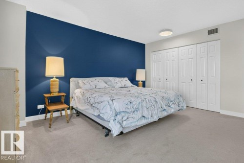 Expansive room featuring a prominent blue accent wall and neutral carpeting - #804 11027 87 Av Nw, Edmonton, AB - Indoor Photo Showing Bedroom