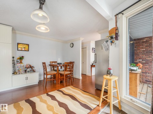 Bright, open-concept living area featuring wood-finish flooring throughout, recessed ceiling lighting, and a wood dining table with matching chairs - 10912 5 Avenue Sw, Edmonton, AB - Indoor