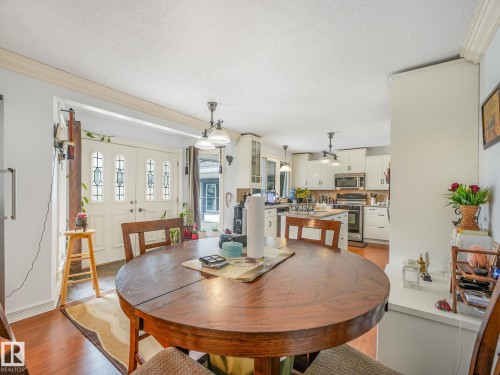 Wood-finish flooring, white double entry doors with decorative glass, recessed lighting, and a kitchen with white cabinetry - 10912 5 Avenue Sw, Edmonton, AB - Indoor Photo Showing Dining Room
