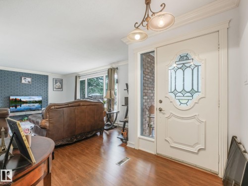Welcoming foyer with decorative leaded-glass entry door, warm wood-finish flooring, and ornamental pendant lighting - 10912 5 Avenue Sw, Edmonton, AB - Indoor