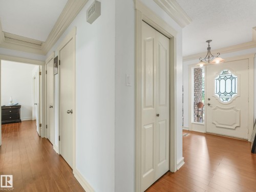 Hallway featuring warm wood-finish flooring, multiple six-panel doors with brushed nickel hardware, crown molding, and recessed ceiling lighting - 10912 5 Avenue Sw, Edmonton, AB - Indoor Photo Showing Other Room