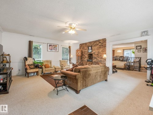 Living area featuring carpet flooring, a ceiling fan, and a partial exposed brick accent wall - 10912 5 Avenue Sw, Edmonton, AB - Indoor Photo Showing Living Room
