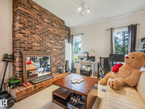 Brick fireplace with hearth and mantel - 10912 5 Avenue Sw, Edmonton, AB - Indoor Photo Showing Living Room With Fireplace