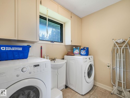 Laundry area featuring upper cabinetry, a single window, a pedestal sink with a base cabinet, and tile flooring - 10912 5 Avenue Sw, Edmonton, AB - Indoor Photo Showing Laundry Room