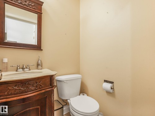 Carved wood vanity with an integrated basin, framed mirror, and two-handle faucet - 10912 5 Avenue Sw, Edmonton, AB - Indoor Photo Showing Bathroom