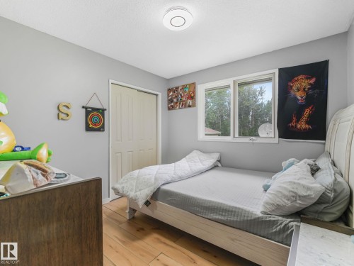 Wood-finish flooring, white bi-fold closet doors, and a double window - 10912 5 Avenue Sw, Edmonton, AB - Indoor Photo Showing Bedroom