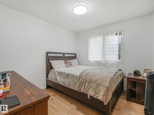 Light wood-finish flooring, white walls, and a ceiling-mounted light fixture - 10912 5 Avenue Sw, Edmonton, AB - Indoor Photo Showing Bedroom