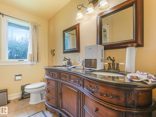 Dual vanity with dark wood-finish cabinetry, integrated sinks, and bronze-finish faucets - 10912 5 Avenue Sw, Edmonton, AB - Indoor Photo Showing Bathroom