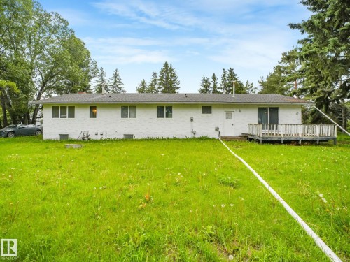 White brick exterior with multiple windows, a rear entry door, and a wooden deck - 10912 5 Avenue Sw, Edmonton, AB - Outdoor