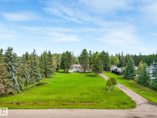 Expansive green space with mature trees, a long driveway, and a residential structure in the background - 10912 5 Avenue Sw, Edmonton, AB - Outdoor With View