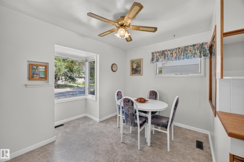 Bright dining area with a bay window, ceiling fan, wood-finish countertop, and built-in shelving - 5207 48 Avenue, Leduc, AB - Indoor Photo Showing Dining Room