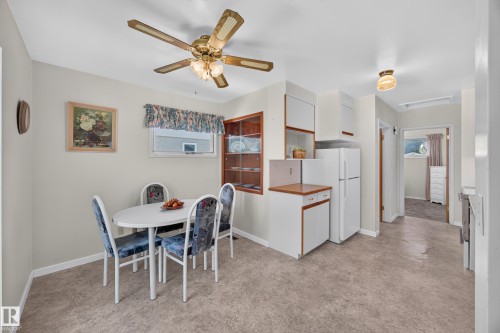 Recessed wall cabinetry, ceiling fan with integrated lighting, window with valance, built-in display cabinet, and neutral flooring - 5207 48 Avenue, Leduc, AB - Indoor Photo Showing Dining Room