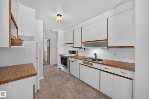 Updated kitchen with white cabinetry and wood-finish countertops - 5207 48 Avenue, Leduc, AB - Indoor Photo Showing Kitchen With Double Sink