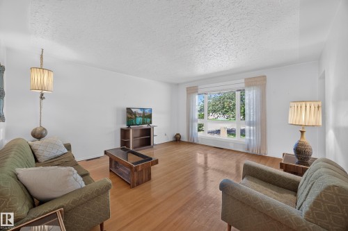 Hardwood flooring, painted walls, and a large window with sheer curtains - 5207 48 Avenue, Leduc, AB - Indoor Photo Showing Living Room