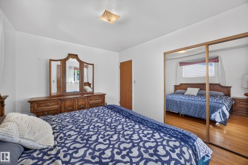 Hardwood-style flooring throughout, ceiling-mounted light fixture, and mirrored sliding closet doors - 5207 48 Avenue, Leduc, AB - Indoor Photo Showing Bedroom