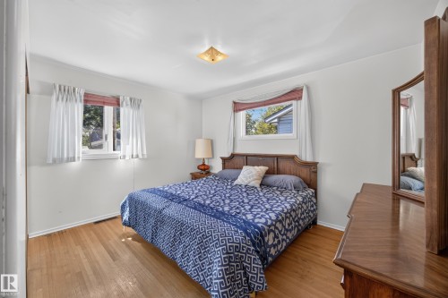 Hardwood flooring throughout, two windows, and a ceiling-mounted light fixture - 5207 48 Avenue, Leduc, AB - Indoor Photo Showing Bedroom