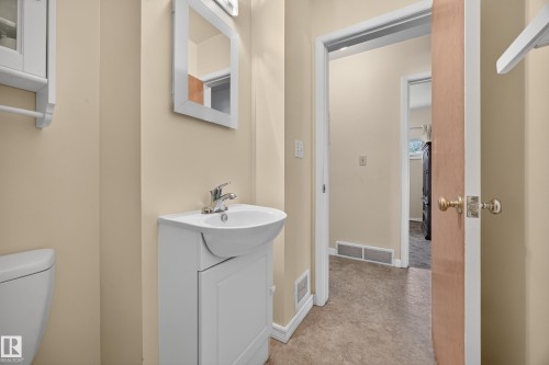 Pedestal vanity with single basin sink, wall-mounted mirror, and wood-finish flooring - 5207 48 Avenue, Leduc, AB - Indoor Photo Showing Bathroom
