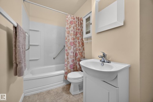 Tub and shower combination with grab bars, toilet, vanity with integrated sink, and wall-mounted medicine cabinet - 5207 48 Avenue, Leduc, AB - Indoor Photo Showing Bathroom