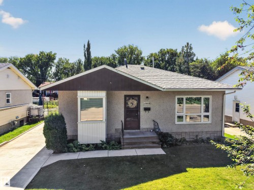 Stucco exterior with a peaked roofline, front bay window, and a concrete pathway leading to the entry - 5207 48 Avenue, Leduc, AB - Outdoor