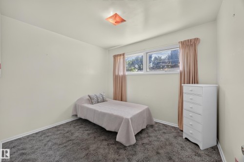 Carpeted room featuring a ceiling-mounted light fixture and dual windows with white trim - 5207 48 Avenue, Leduc, AB - Indoor Photo Showing Bedroom