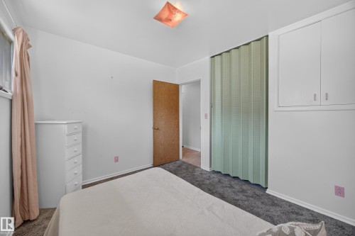 Wall-to-wall carpeting with built-in cabinetry and a folding closet door - 5207 48 Avenue, Leduc, AB - Indoor Photo Showing Bedroom