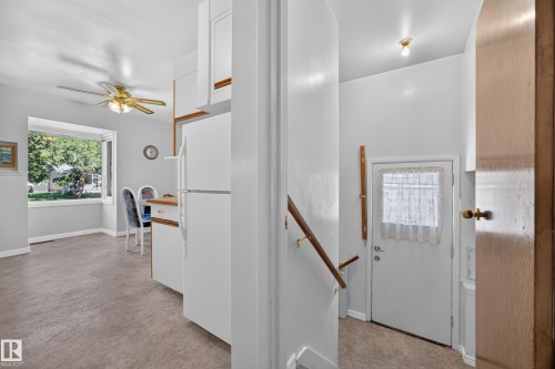 Built-in white cabinetry with wood-finish accents, large bay window, ceiling fan with integrated lighting, wood-finish handrail - 5207 48 Avenue, Leduc, AB - Indoor Photo Showing Other Room