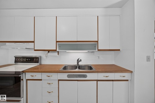 White cabinetry with wood-finish trim and brass hardware - 5207 48 Avenue, Leduc, AB - Indoor Photo Showing Kitchen With Double Sink