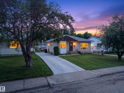 Single-story residence featuring a concrete driveway, a front lawn, and mature trees - 5207 48 Avenue, Leduc, AB - Outdoor