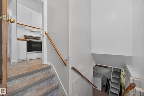 White cabinetry with wood-finish trim, built-in oven, and wood handrails - 5207 48 Avenue, Leduc, AB - Indoor Photo Showing Other Room