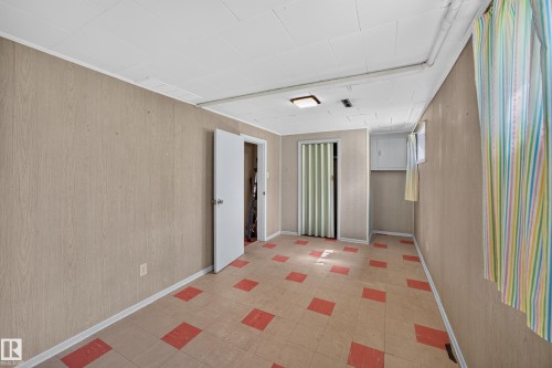 Room with wood-panel walls, patterned tile flooring, and a white ceiling - 5207 48 Avenue, Leduc, AB - Indoor