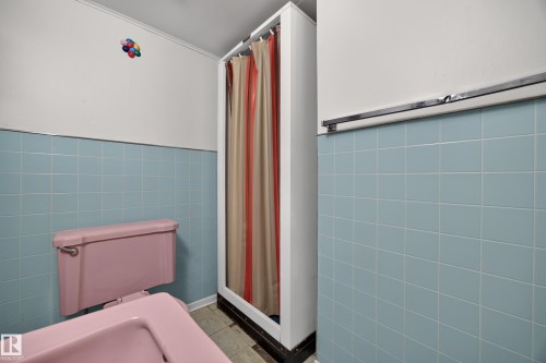 Blue wall tiling with a pink toilet and pink sink - 5207 48 Avenue, Leduc, AB - Indoor Photo Showing Bathroom