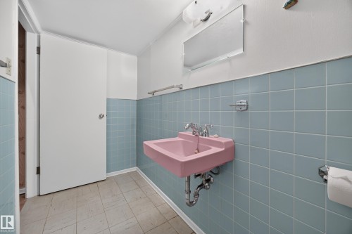 Wall-mounted sink, tiled walls, wall-mounted mirror, and tile flooring - 5207 48 Avenue, Leduc, AB - Indoor
