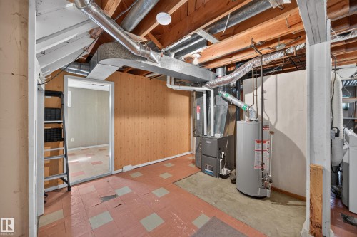 Exposed ceiling joists and ductwork, wood-paneled wall, cement flooring, and water heater - 5207 48 Avenue, Leduc, AB - Indoor Photo Showing Basement